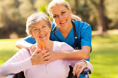 Meadowbrook Senior Living at Black River Falls, nursing home in Black River Falls, WI — Caregiver and resident smiling in an outdoor setting