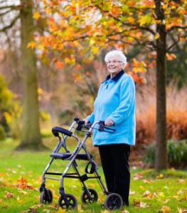 Arbor Lake Health & Rehab, LLC, Nursing Home in Auburn, AL — Elderly woman standing outdoors with a walker in autumn