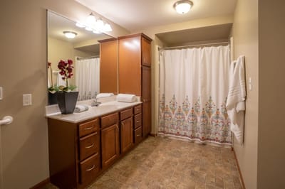 Well-lit bathroom with wooden cabinets and decorative towels