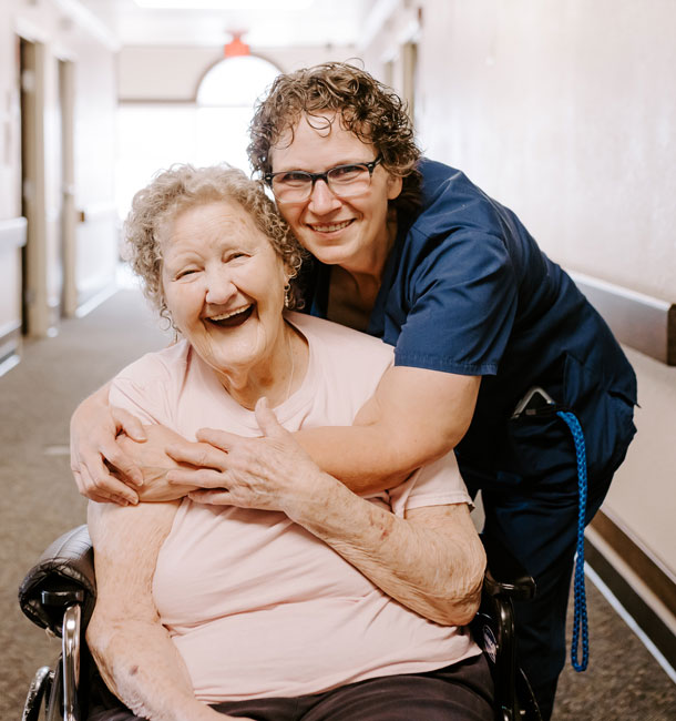 A caregiver hugging a resident in a hallway