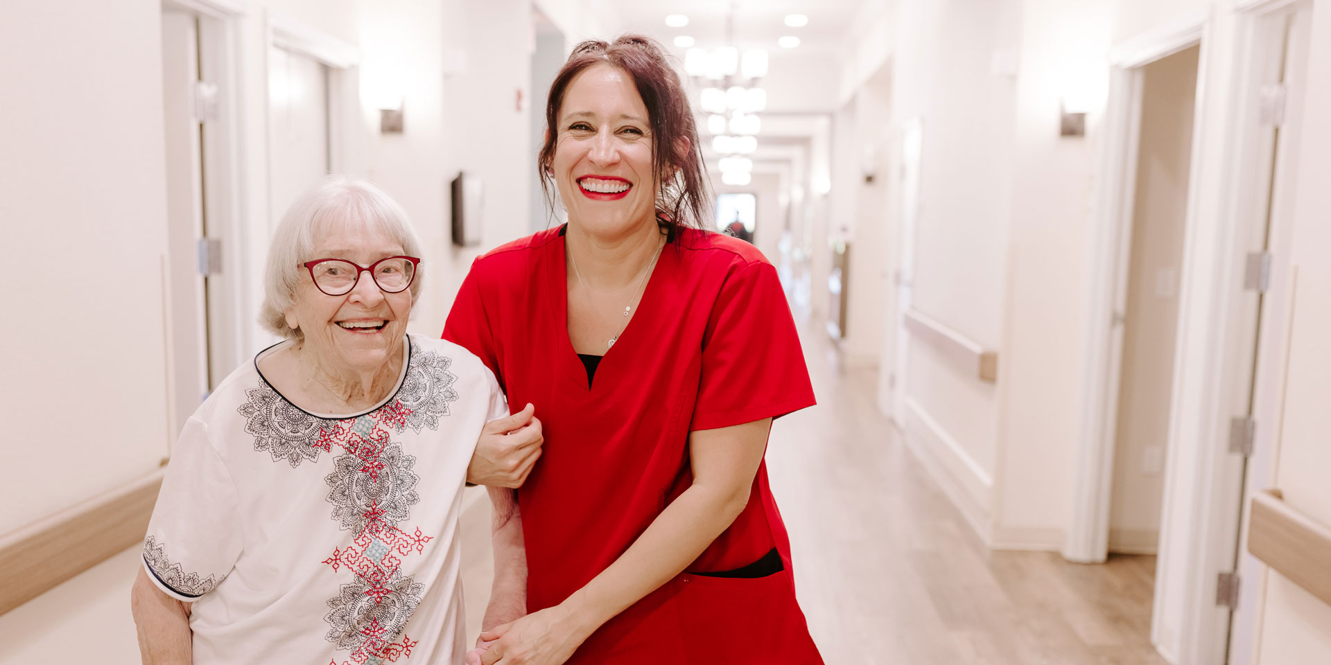 Resident and staff member smiling in a hallway