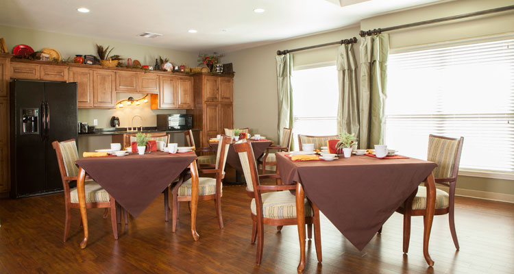 Bright dining area with set tables and kitchen in background