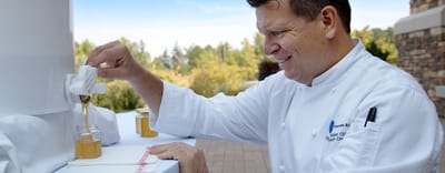 Chef serving honey from a dispenser outdoors