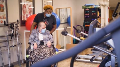 A caregiver assisting a resident in a rehabilitation area
