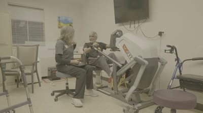 Resident using therapy equipment with staff assistance