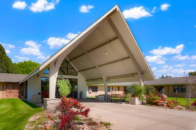Entrance view of a senior living facility surrounded by greenery