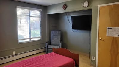 A cozy resident room with a bed and armchair