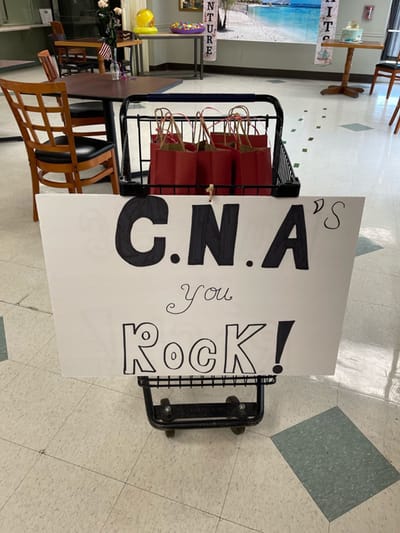 Sign celebrating CNAs with gifts on a cart