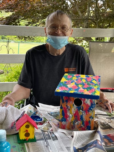Resident painting colorful birdhouses outdoors