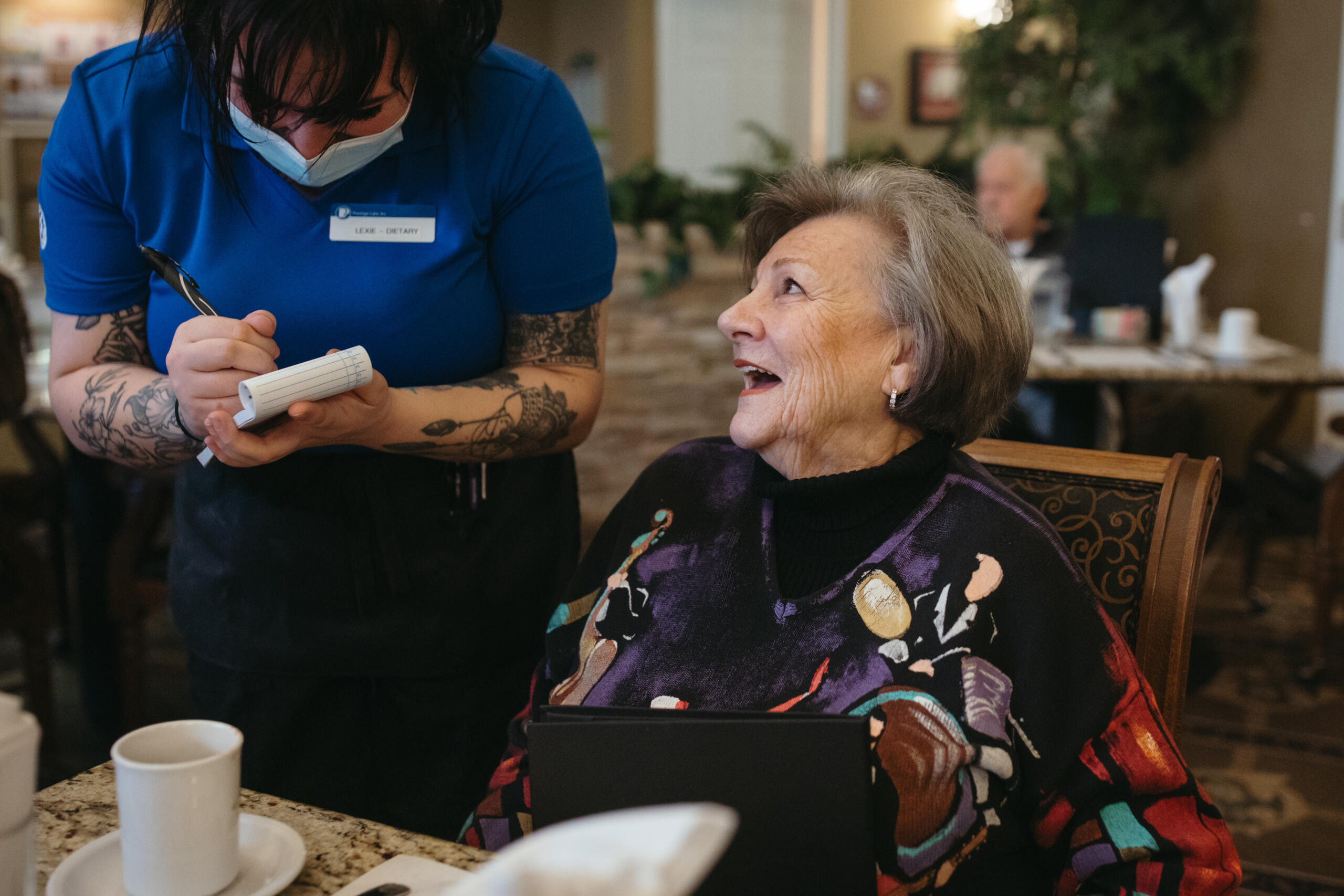 Resident enjoying interaction with staff in dining area
