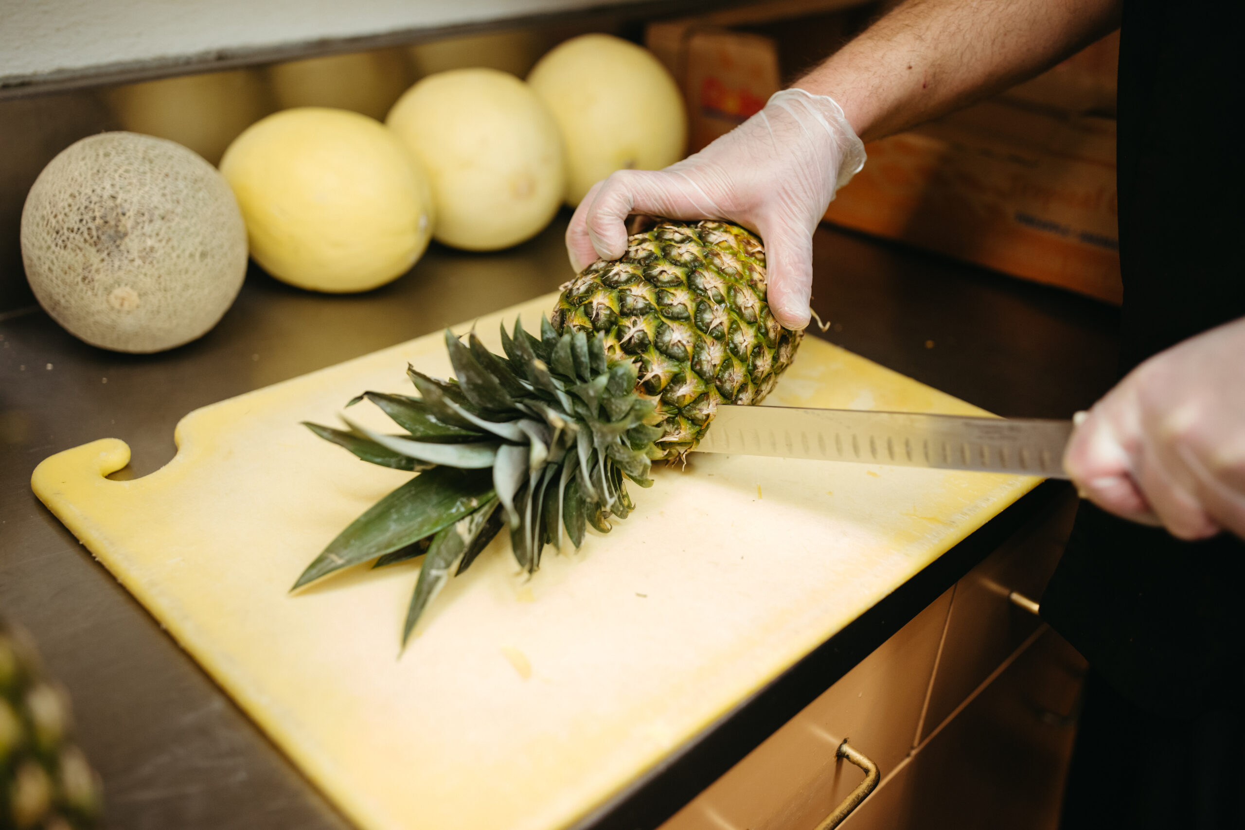 A kitchen scene with a person cutting a pineapple
