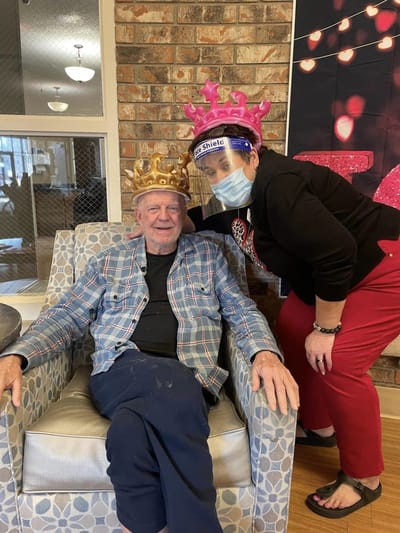 Resident and staff member celebrating with crowns in a common area