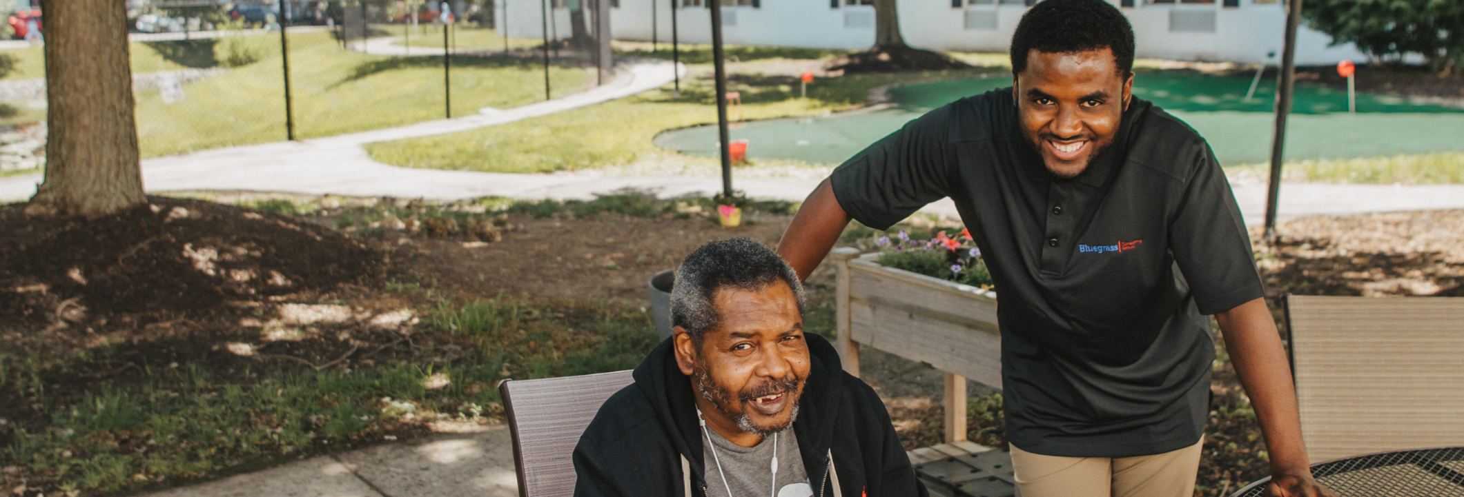 A caregiver and resident smiling outdoors in the facility