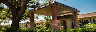 Exterior view of a senior living facility with large trees