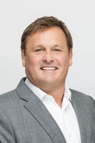 Smiling man in a gray blazer.