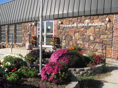 Exterior view of Truman Lake Manor with flower beds