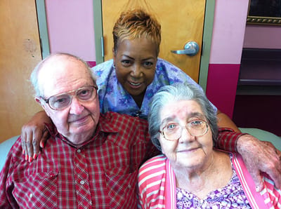 Two residents smiling with a staff member