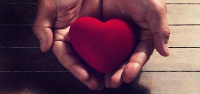 Hands holding a red heart symbol