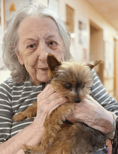 An elderly woman holding a small dog in her lap