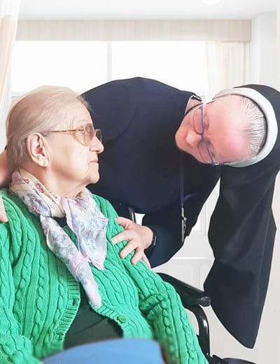 A caregiver interacting with an elderly resident in a bright room