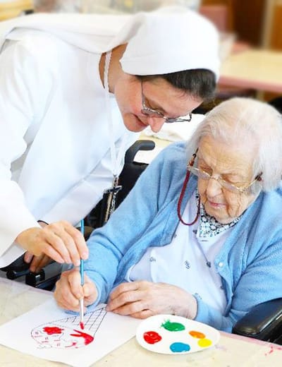 Staff assisting a resident with painting activity