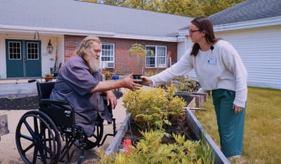 Resident gardening with staff assistance outside