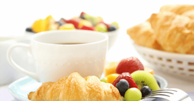 A plate of croissants and fresh fruit with coffee