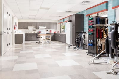 Physical therapy room with exercise equipment and kitchen area