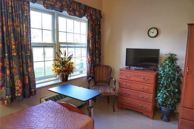 Cozy private room with a window, clock, and TV
