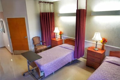 A shared resident room with two beds and lamps