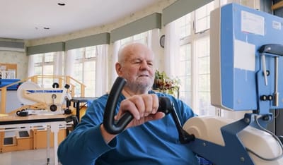 Senior resident using exercise equipment in a bright room