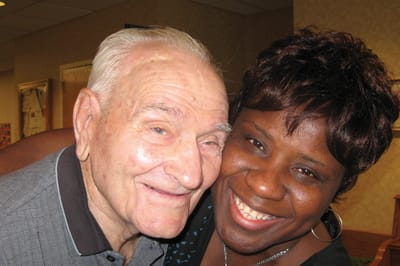 Senior resident and staff member happily posing together