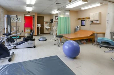 A physical therapy room with exercise equipment and mats
