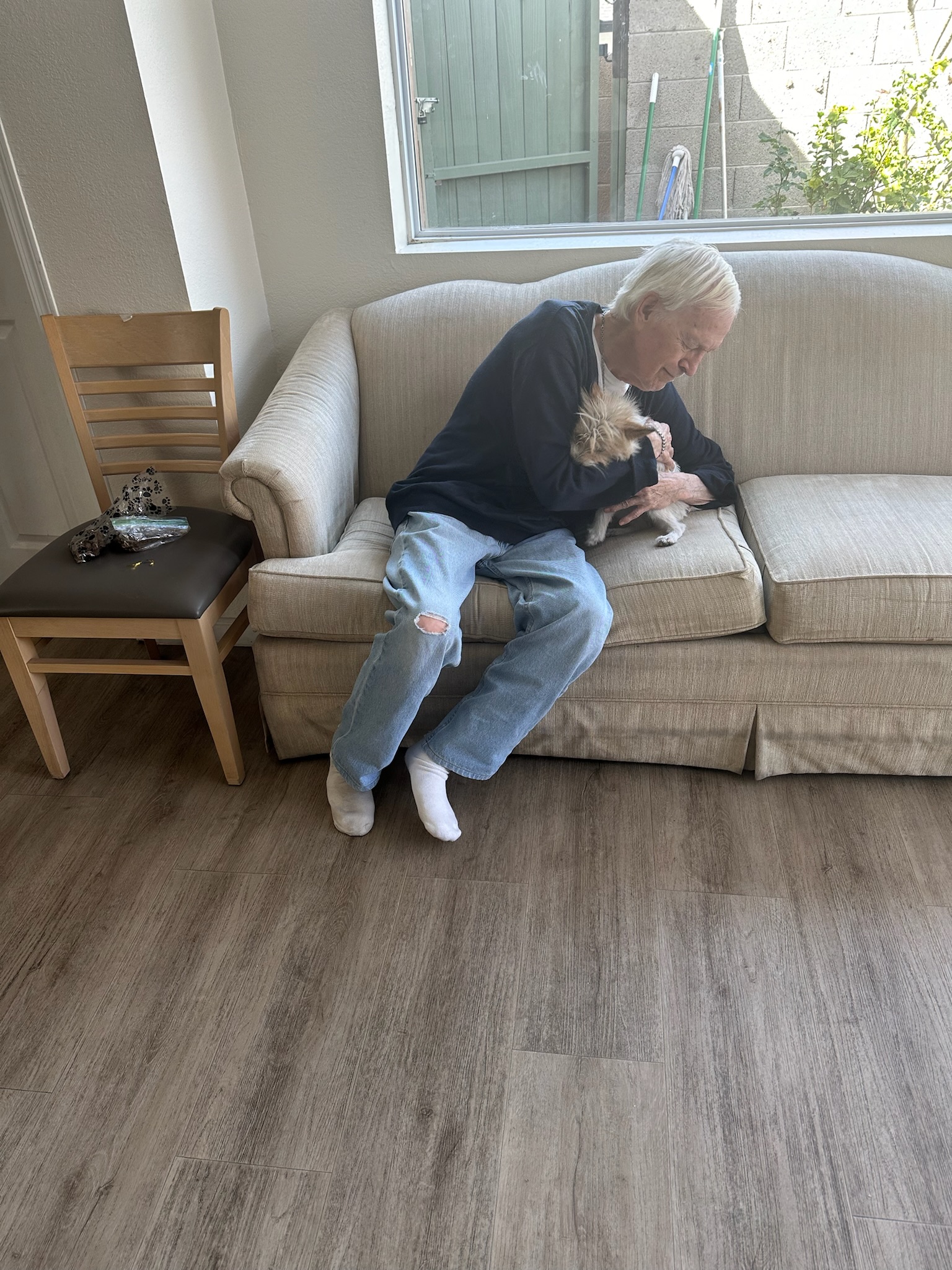 A resident sitting on a couch with a small dog