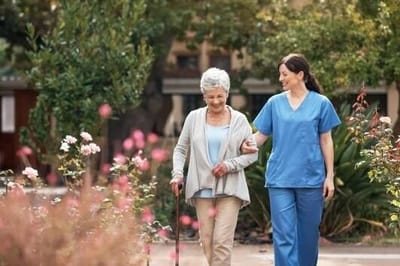 Senior resident walking in a garden with staff