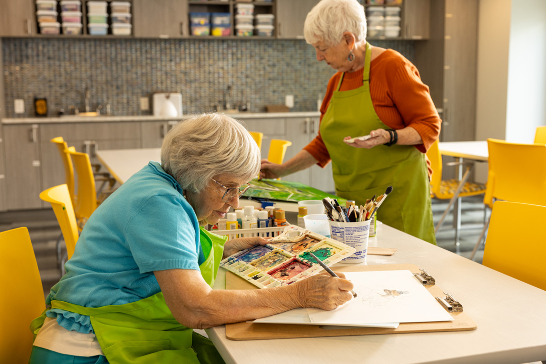 Residents engaged in a painting activity in a bright art room