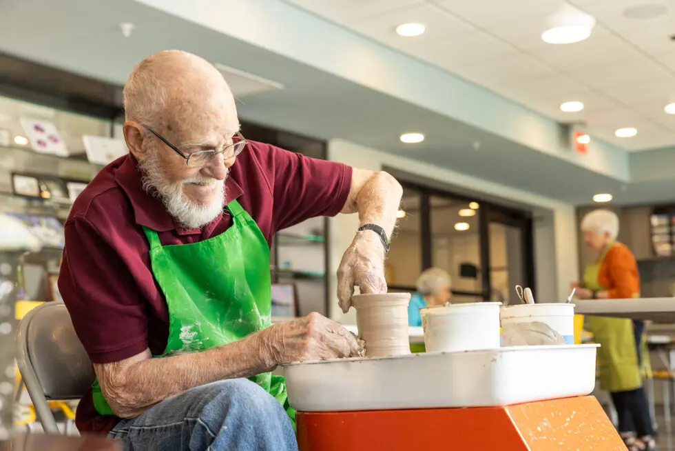 An elderly man engaged in pottery activity