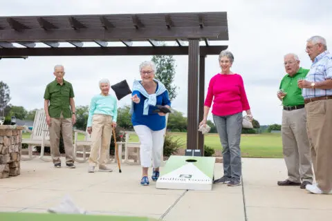 Residents playing cornhole in an outdoor space