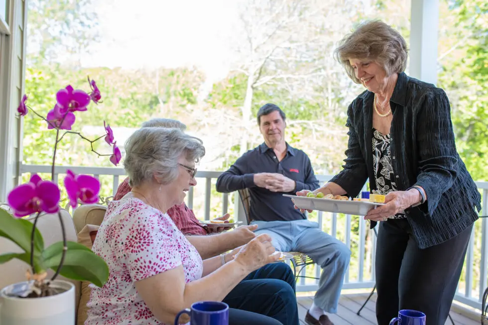 Residents enjoying snacks outdoors with staff assistance