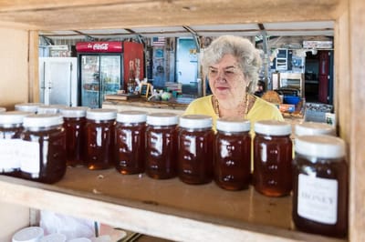 Senior woman looking at jars of honey in a market