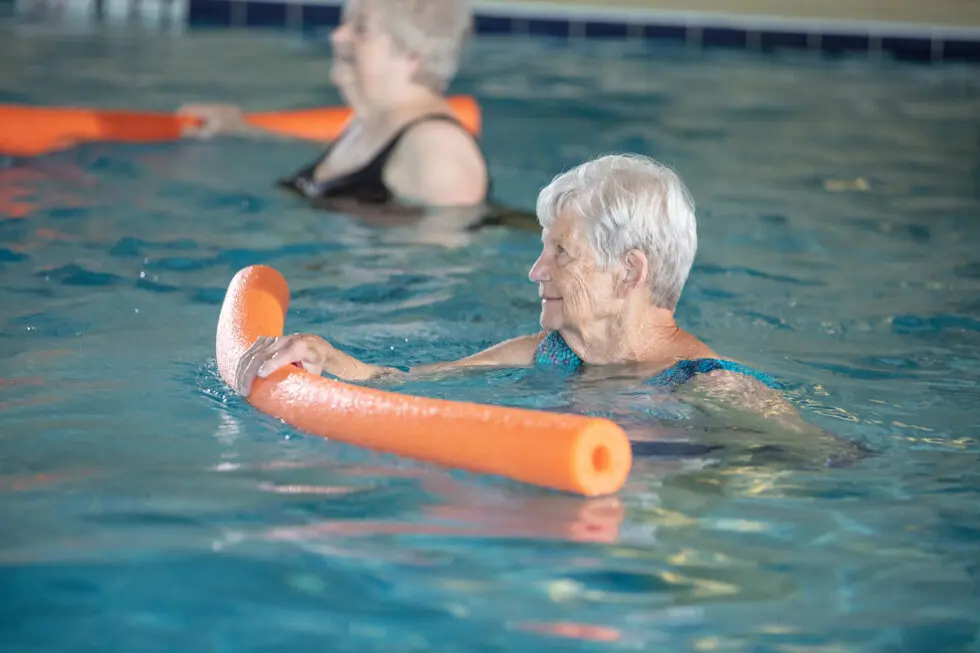 Seniors participating in a water aerobics class in a pool