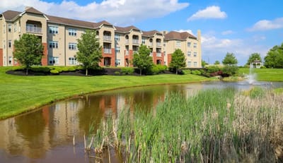 Exterior view of a senior living facility by a pond