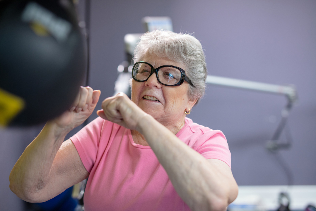 Senior resident exercising with boxing gloves indoors