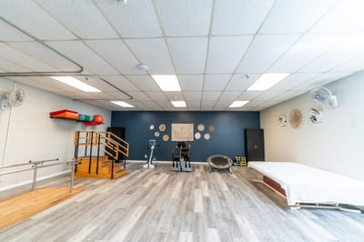 Physical therapy room with exercise equipment and wooden railing