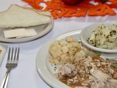 A plate of food with chicken, potatoes, and bread