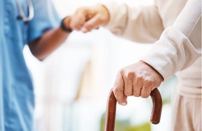 Close-up of a caregiver assisting a resident with a cane