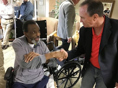 Resident and staff member shaking hands in common area
