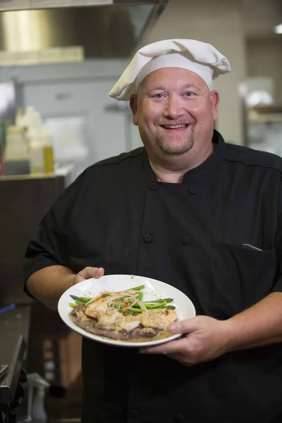 Chef presenting a beautifully plated dish in the kitchen