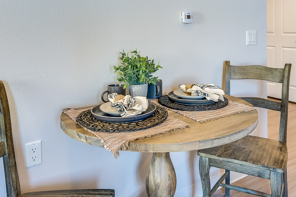 A dining table set with plates and plants