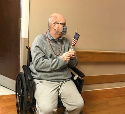 Resident in a wheelchair holding a small American flag